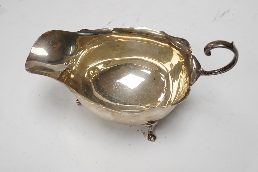 A Victorian silver cream jug, maker JR, London, 1884, together with a later silver sauce boat, pepperette and dish. Condition - poor to fair